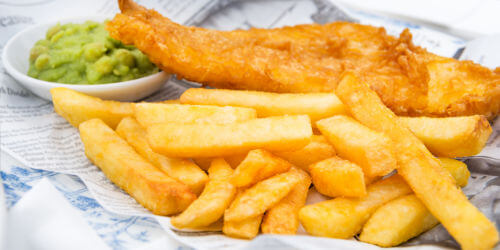 A portion of fish, chips, and mushy peas meal